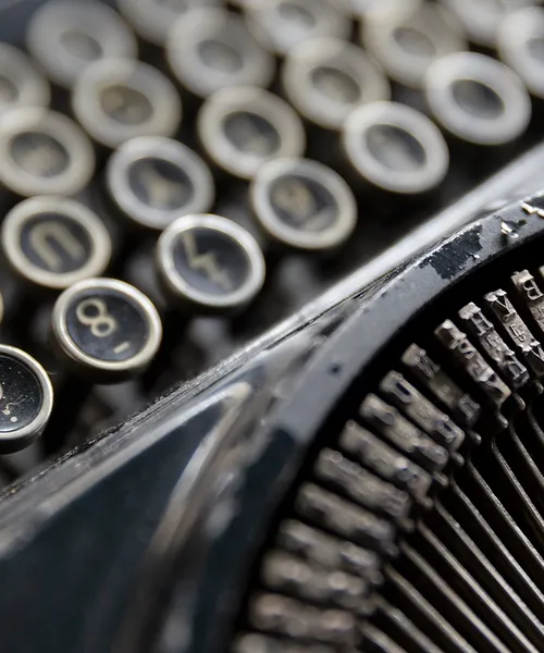 Nahaufnahme einer alten Schreibmaschine mit sichtbaren Tasten und Metalllettern.